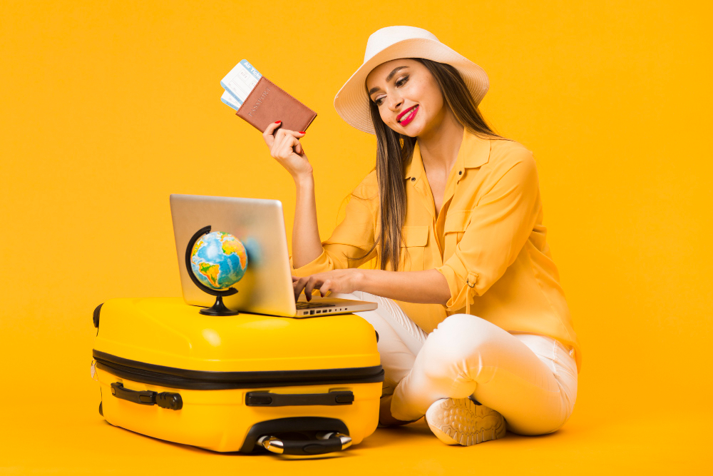 woman sitting and working on laptop, holding plane ticket